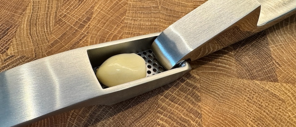 Eine Knoblauchzehe liegt in der geöffneten Gourmet Easy Knoblauchpresse.