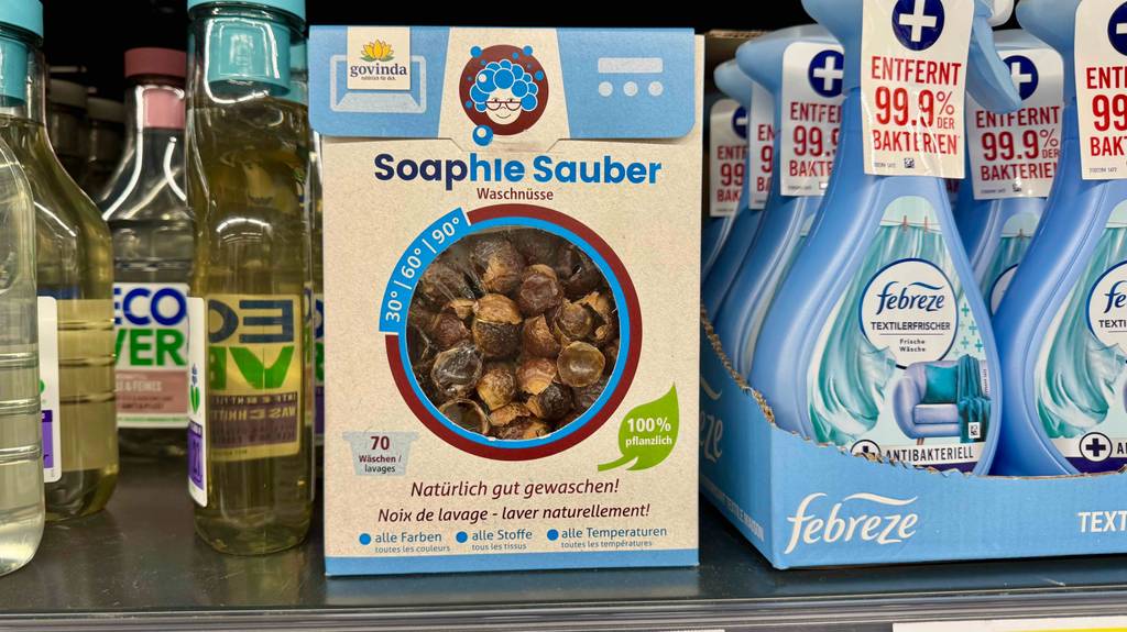 Mehrere Packungen Waschnüsse stehen zum testen in einem Regal zwischen anderen Haushaltsprodukten.
