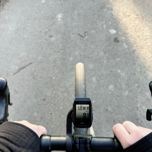 Der Sigma ROX 11.1 EVO ist während der Fahrt an einem Rennrad befestigt. Die Hände des Fahrers halten den Lenker, während der Fahrradcomputer die Geschwindigkeit anzeigt.