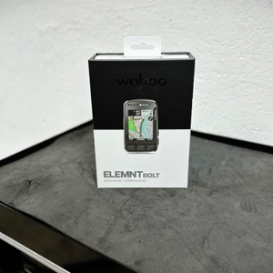Die Originalverpackung des Wahoo ELEMNT BOLT V2 steht auf einer schwarzen Oberfläche. Das Design zeigt das Gerät mit einer Karte auf dem Display.