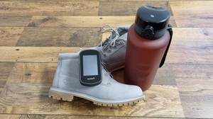Schuhe, Trinkflasche und GPS-Gerät liegen auf dem Boden.