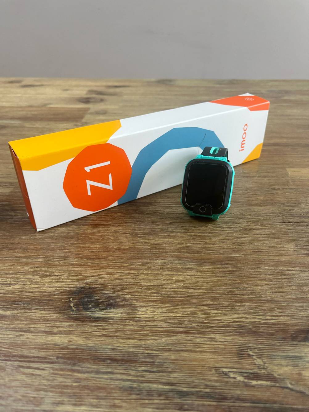 Eine GPS-Uhr im Test neben der Originalverpackung auf einer Holzfläche.