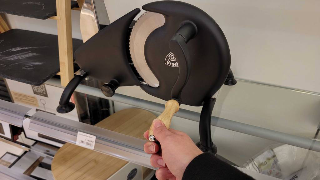 Brotschneidemaschine manuell im Test: Eine Hand dreht an der Kurbel.