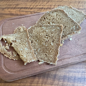 Unterschiedlich dick geschnittene Scheiben Vollkornbrot liegen auf einem Holzbrett