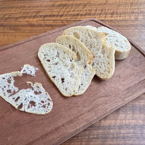 Unterschiedlich dick geschnittenes Weißbrot liegt auf einem Holzbrett