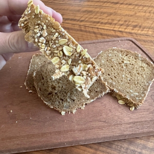 Eine Hand hält eine dick geschnittene Scheibe Vollkornbrot fest