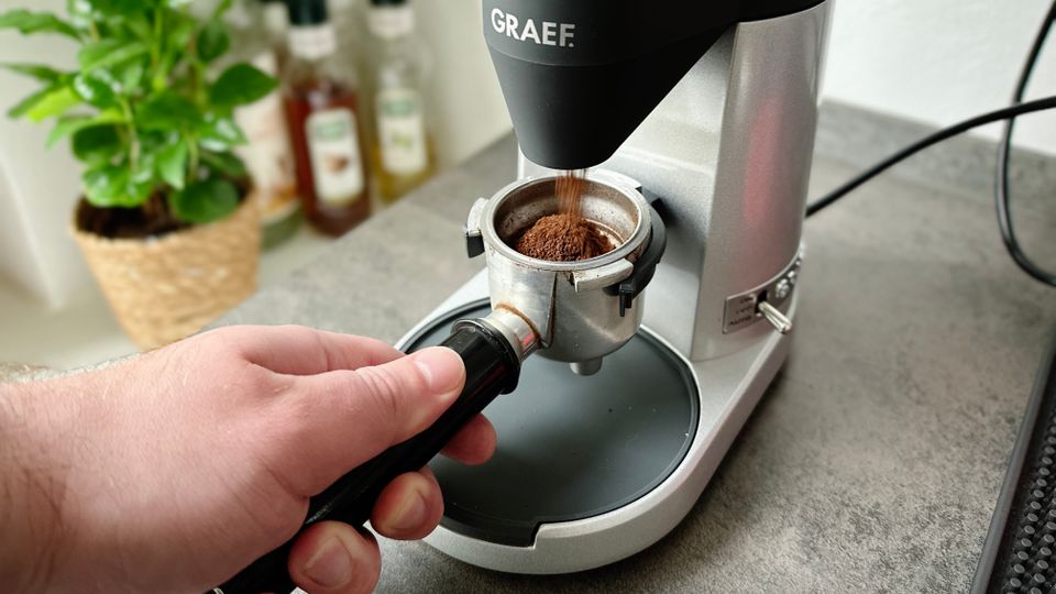 Espressomühlen im Test: Ein Siebträger wird mit Kaffeepulver von einer Espressomühle befüllt.