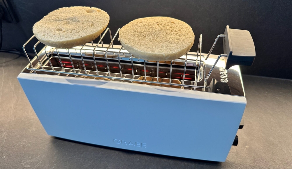 Ein geschnittenes Brötchen liegt auf dem dafür vorgesehenem Aufsatz des Graef TO91.