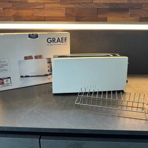 Der Graef TO91 steht mit seinem Karton und seinen Aufsätzen auf einer Küchenarbeitsplatte.