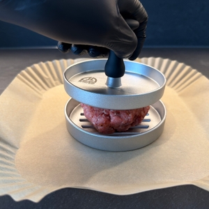 Der Pressstempel vom Gräwe-Hamburgerpressen-Set wird auf ein Fleischbällchen gedrückt