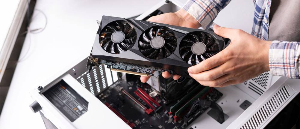 Grafikkarten-Test: Ein Mann baut eine Grafikkarte in einen Computer ein.