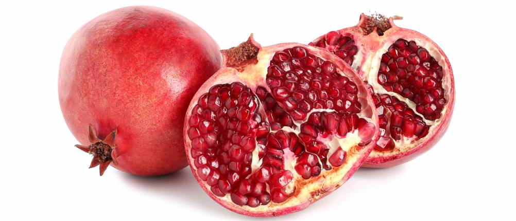 Granatapfel-Entkerner-Test: Ein ganzer Granatapfel liegt neben zwei Granatapfel-Hälften.