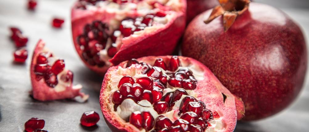 Granatapfel-Entkerner-Test: Ganze und halbierte Granatäfpel mit Kernen.