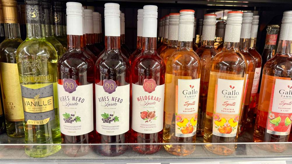 Mehrere Flaschen des Granatapfelwein im Test in einem Verkaufsregal neben anderen Produkten.