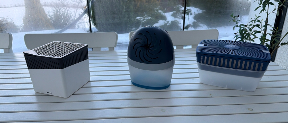 Drei Luftentfeuchter mit Granulat stehen nebeneinander auf einem Tisch