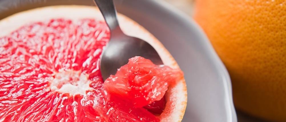 Grapefruitlöffel im Test: Nahaufnahme eines Grapefruitlöffels im Fruchtfleisch einer Grapefruit.