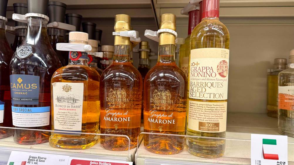 Mehrer Flaschen des getesteten Grappa Amarone in einem Verkaufsregal mit anderen Produkten.