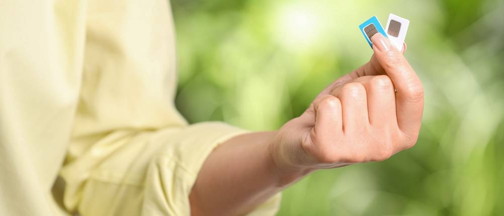 Eine Frau hält zwei SIM-Karten zwischen ihren Fingern in die Luft.
