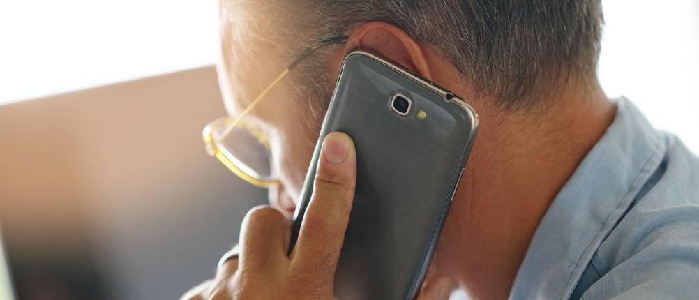 Ein Mann telefoniert mit seinem Smartphone am Ohr.