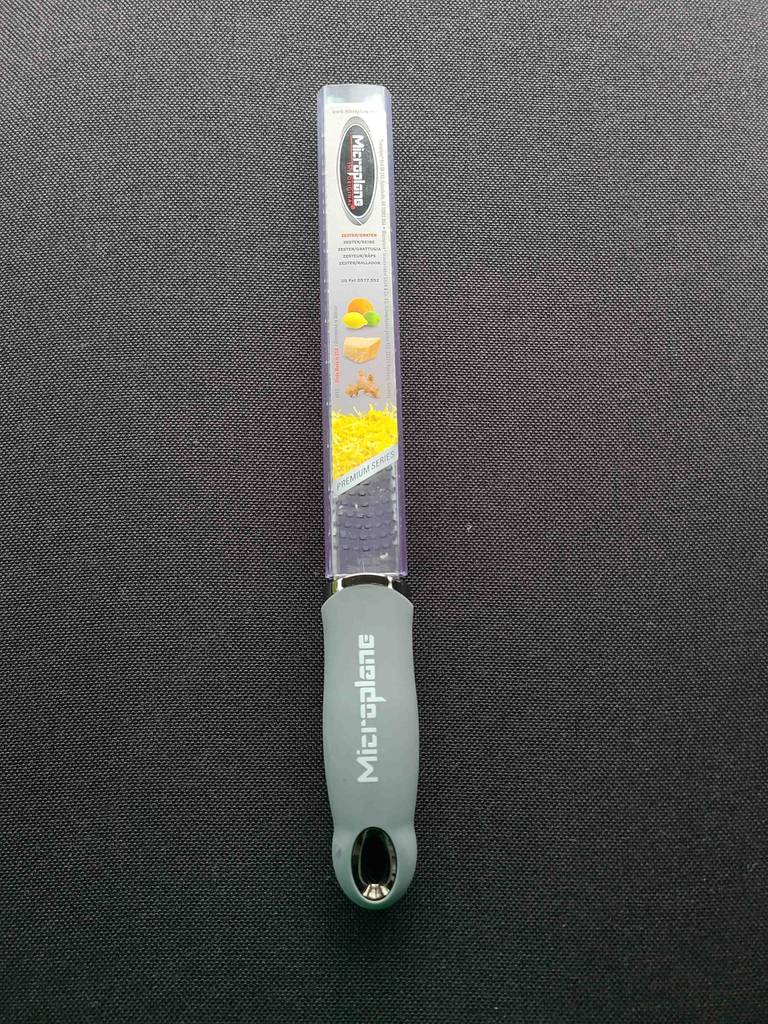 Im Test: Die Microplane-Reibe liegt inklusive Verpackung auf einem grauen Untergrund.