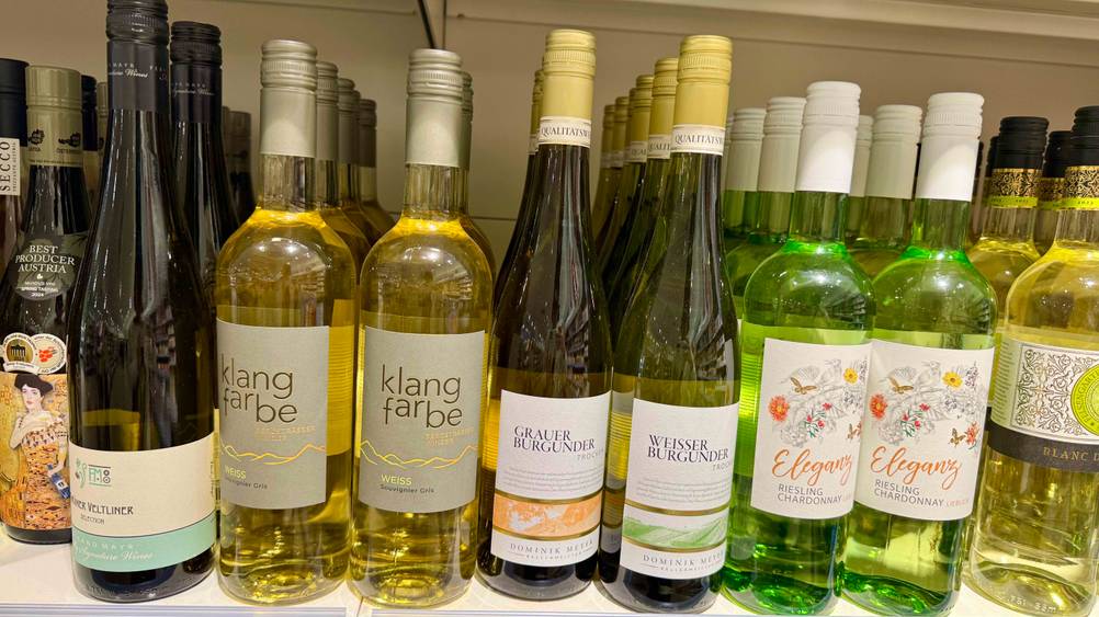 Mehrere Flaschen des Grauburgunder im Test in einem Verkaufsregal neben anderen Weinen.