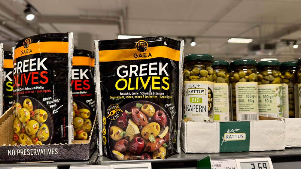Eine Packung der getesteten griechischen Oliven in einem Verkaufsregal neben anderen Produkten.