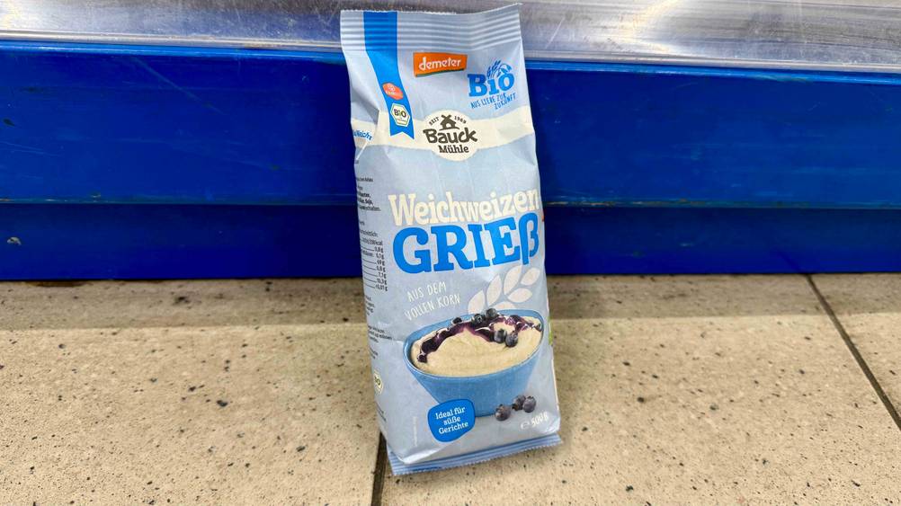 Vor einem Regal auf dem Boden steht eine Packung Grieß im Test.
