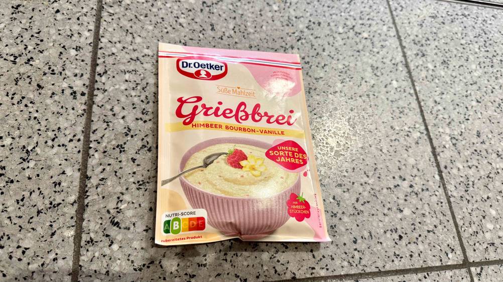 Auf einem Fließenboden liegt eine Packung des getesteten Grießbreis.