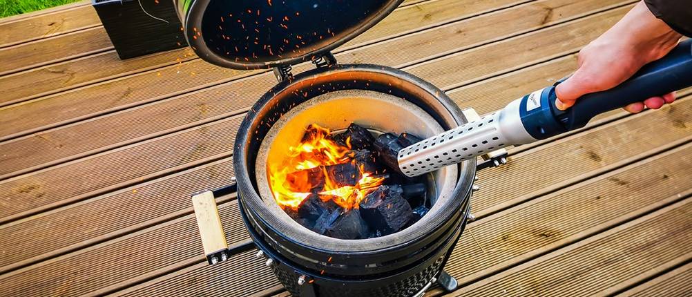 Elektrischer Grillanzünder getestet: Heizstab wird in Richtung eines offenen Grills gehalten.