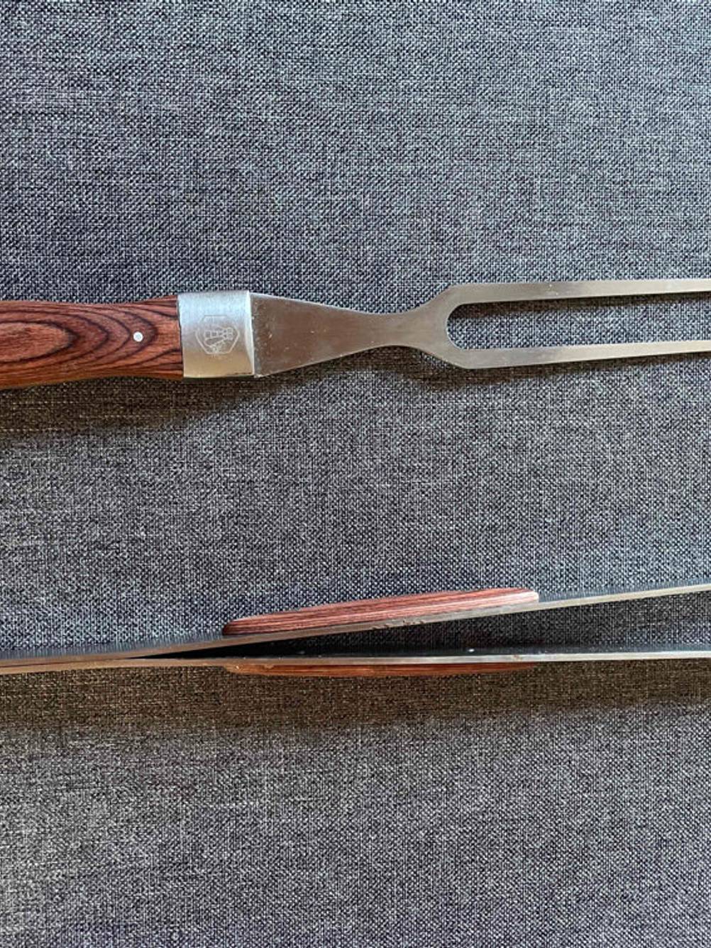 Grillbesteck getestet: Eine Grillgabel und eine Zange auf einer grauen Fläche.