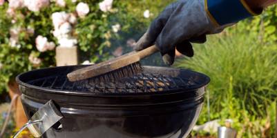 Grillbürste getestet: Person führt eine Grillbürste über den Rost.
