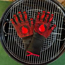 Die getesteten Grillhandschuhe von Primajor liegen auf einem Grillrost.