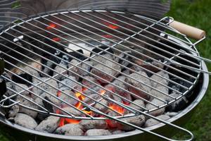 Grillhandschuhe getestet: gluehende Kohlen unter einem Rost.