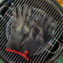 Die getesteten Grillhandschuhe von Weber liegen auf einem Grillrost.