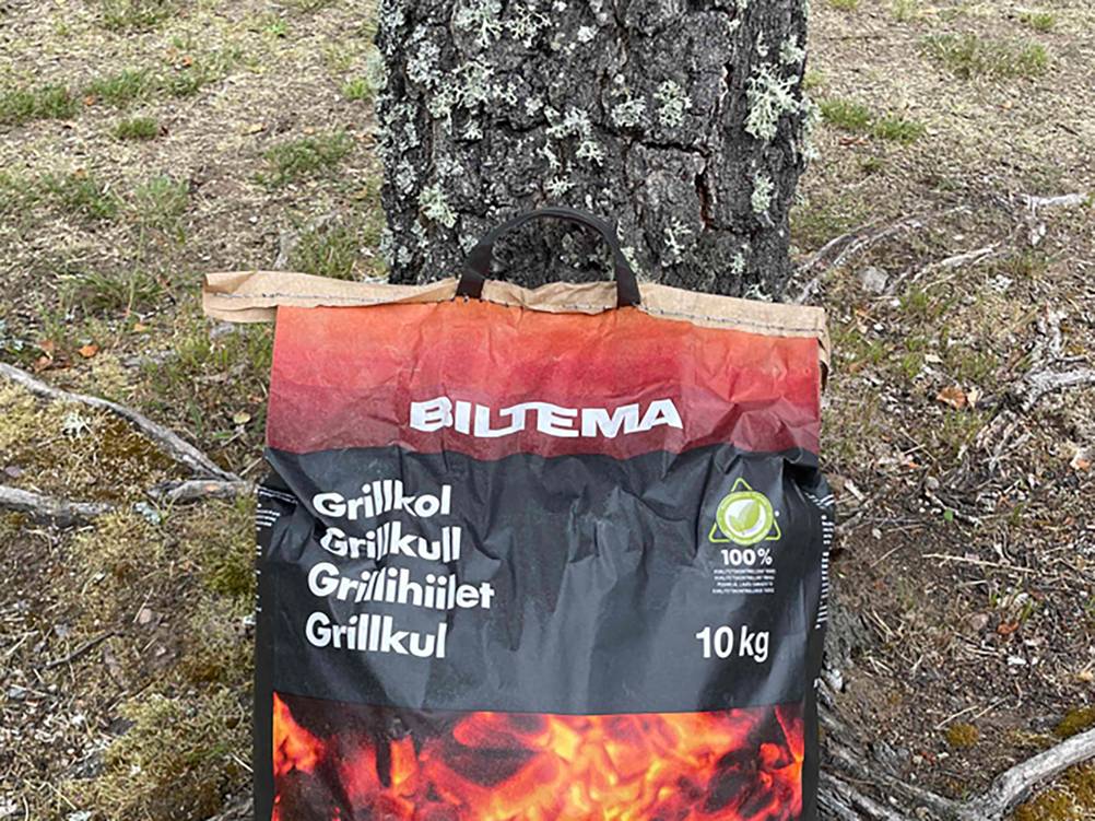 Eine Packung der getesteten Grillkohle lehnt an einem Baum.