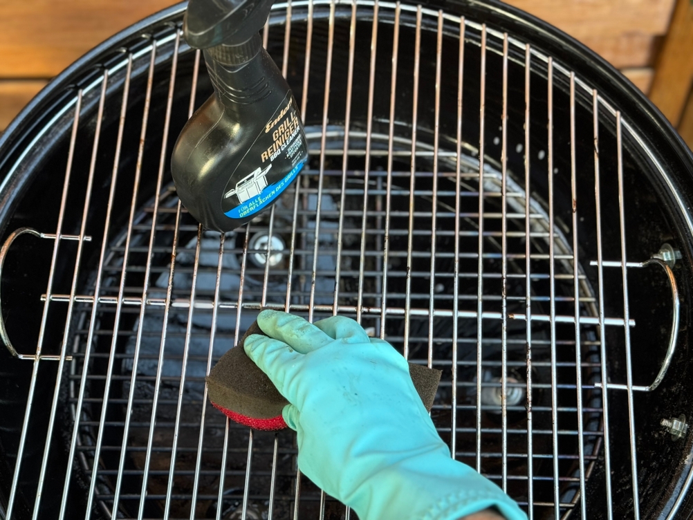 Eine Person reinigt mit einem Schwamm und dem getesteten Grillreiniger von Enders einen Grillrost.