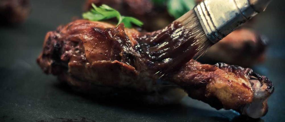 Fleisch wird mit BBQ-Glasur eingepinselt