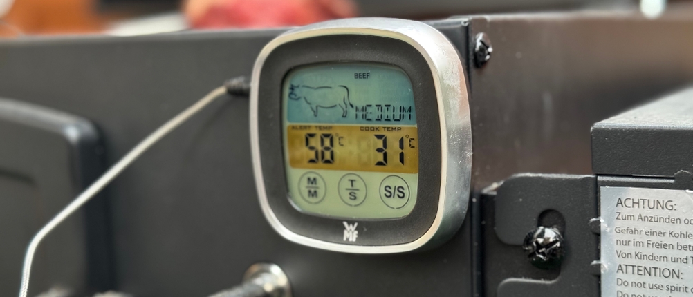 Das getestete Grillthermometer von WMF an einem Grill befestigt.