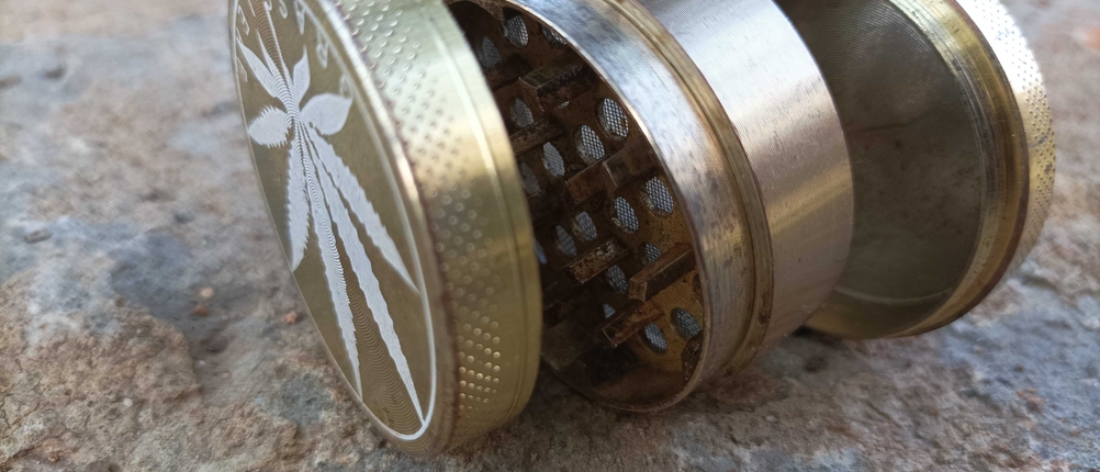 Ein getesteter Grinder liegt seitlich in Einzelteilen auf einer Steinfläche.