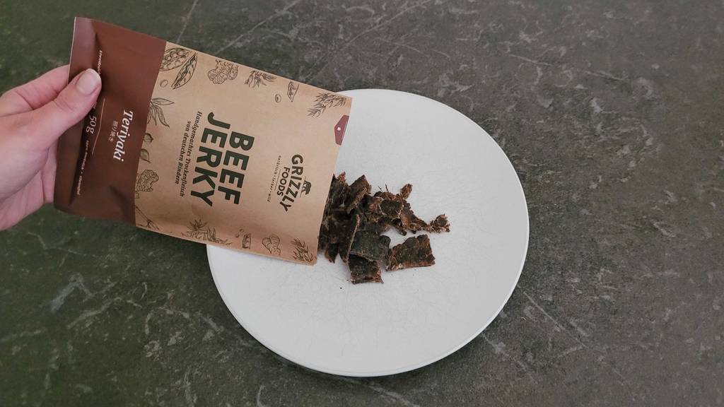 Beef-Jerky wird aus einer Verpackung zum testen auf einen weißen Teller geschüttet.
