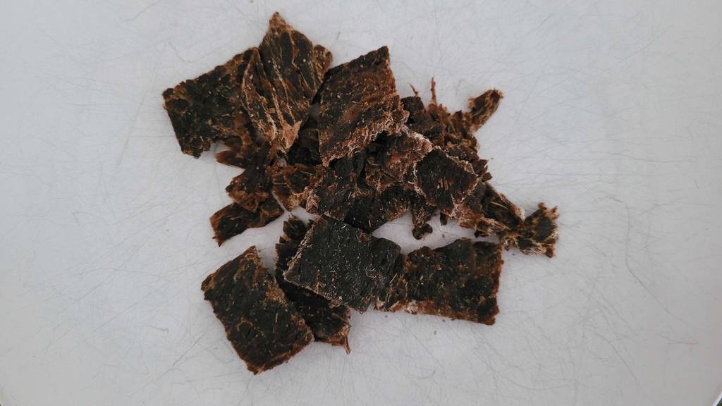 Im Test: Detailansicht einiger Beef-Jerky-Stücke, die auf einem Haufen auf einer weißen Fläche liegen.