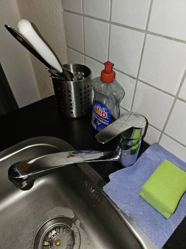 Ansicht von oben einer Edelstahl-Küchenarmatur im Test mit mittlerem Auslauf und Mischbatterie auf einer schwarzen Arbeitsplatte.