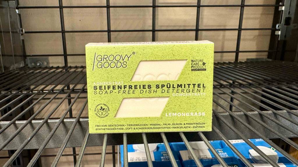 In der grünen Verpackung steht ein seifenfreies, festes Spülmittel im Test auf einem Verkaufsregal.
