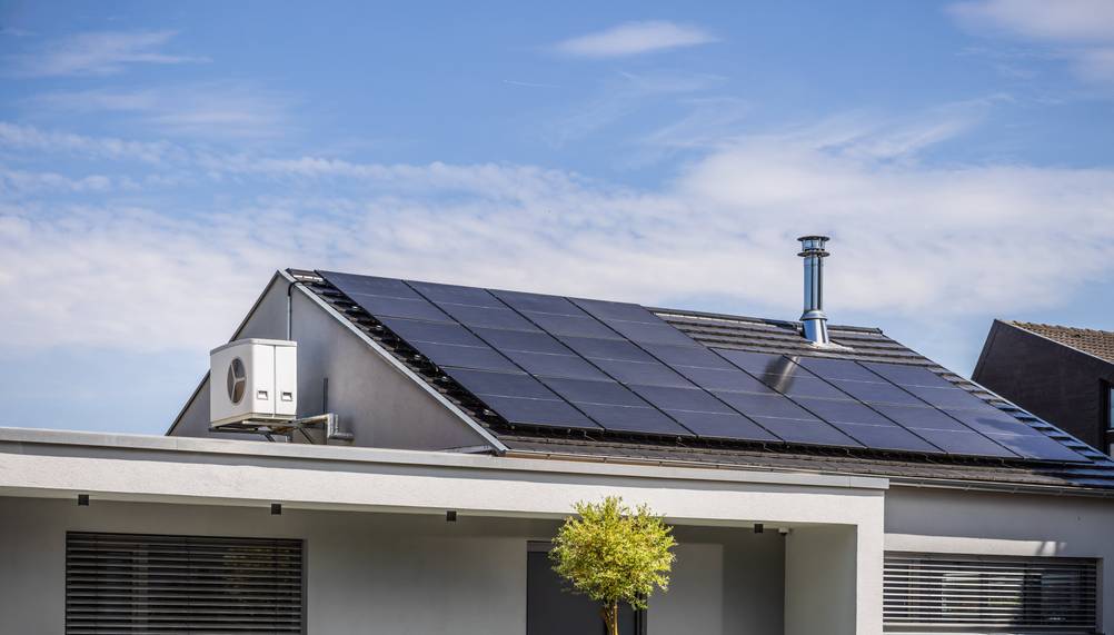 Growatt-Wechselrichter im Test: Ein Haus mit PV-Anlage auf dem Dach und Wärmepumpe am Giebel