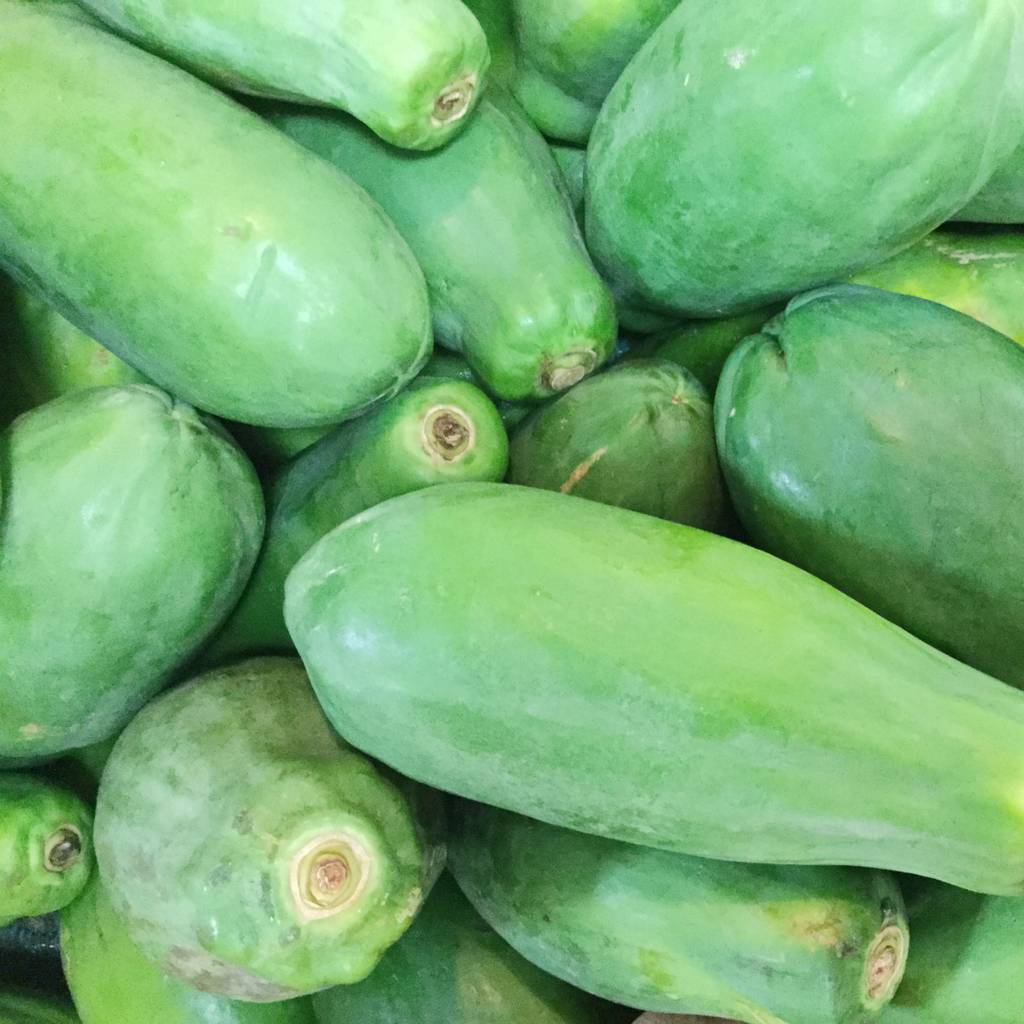 Papain-Test: Mehrere grüne Papayas liegen aufeinander.