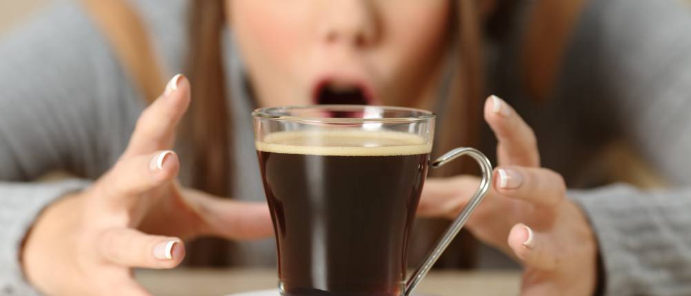 Front view portrait of an amazed woman looking at coffee cup