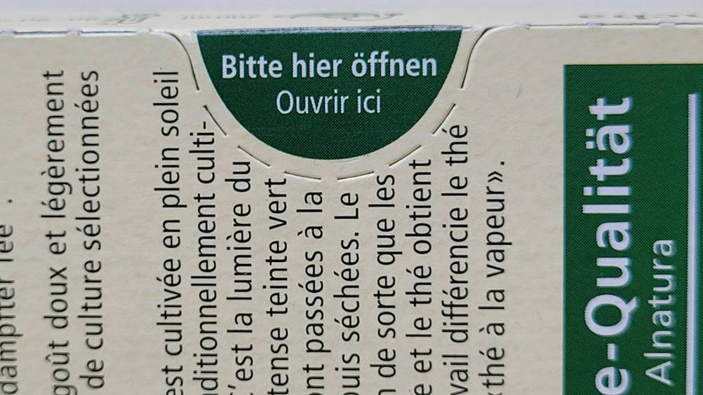 Nahaufnahme einer Packung des getesteten Grüntees mit 'Bitte hier öffnen'.