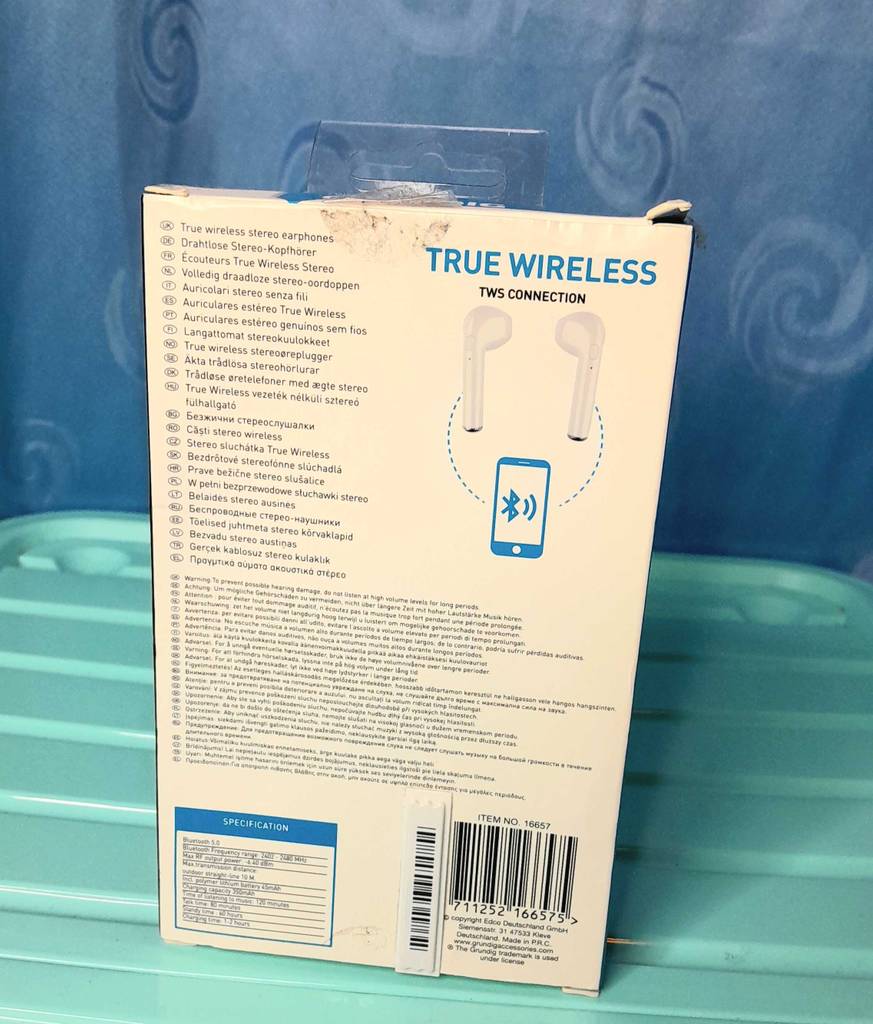 Kopfhörer mit In-Ear Noise Cancelling im Test: Ansicht der weißen Verpackungsrückseite inklusive Produktinformationen eines True Wireless In-Ear-Kopfhörers vor türkisfarbenem Hintergrund.