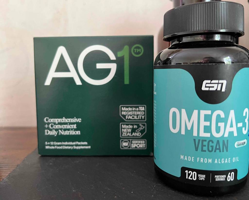 Nahrungsergänzungsmittel für Veganer im Test: zwei verschiedene Produkte stehen in Originalverpackung nebeneinander auf einer dunklen Fläche.