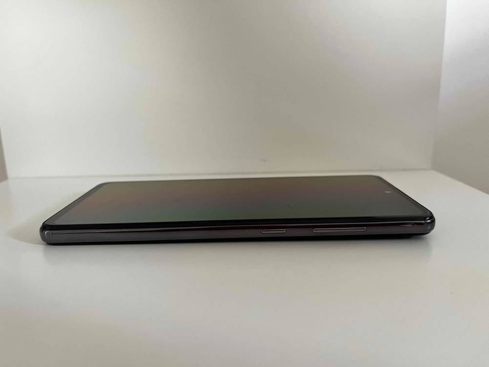 Im Test: Seitenansicht eines günstigen Smartphones mit Bedienelementen auf einer einer hellen Fläche.